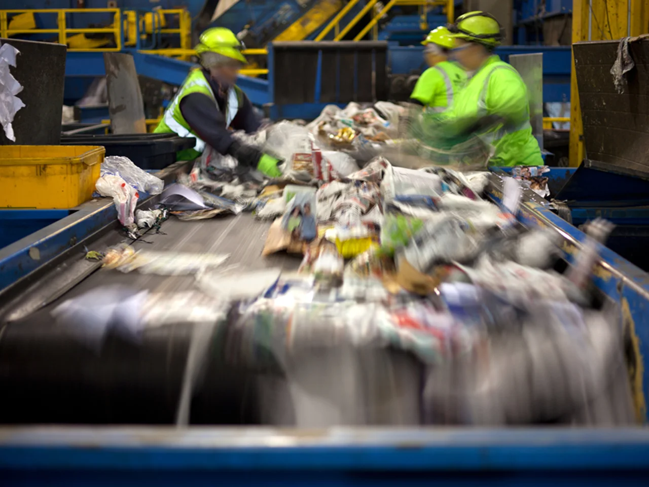 Workers separating paper And plastic on a conveyor belt in a recycling facility