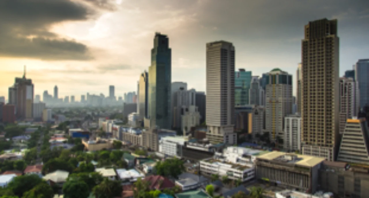 Morning sun shining through clouds onto low and high rise buildings in Makati, Manila Region
