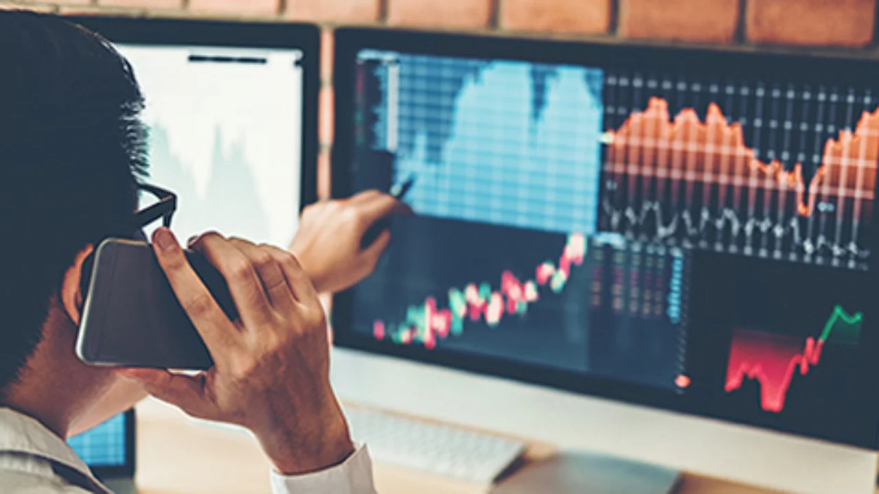 Person looking on charts displayed on his monitor whilst calling