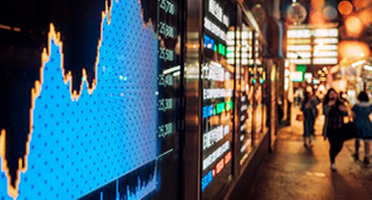 A big display showing a stock chart in a busy street in China