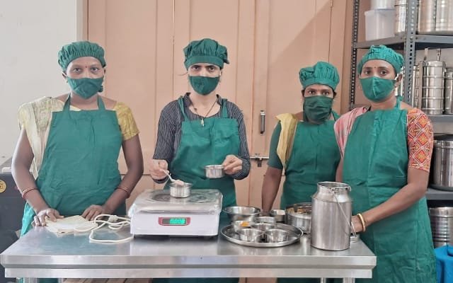 Four Kamla co-operative members wearing green protective clothing