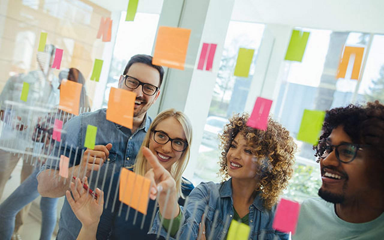 Business team brainstorming in front of glass wall with adhesive notes