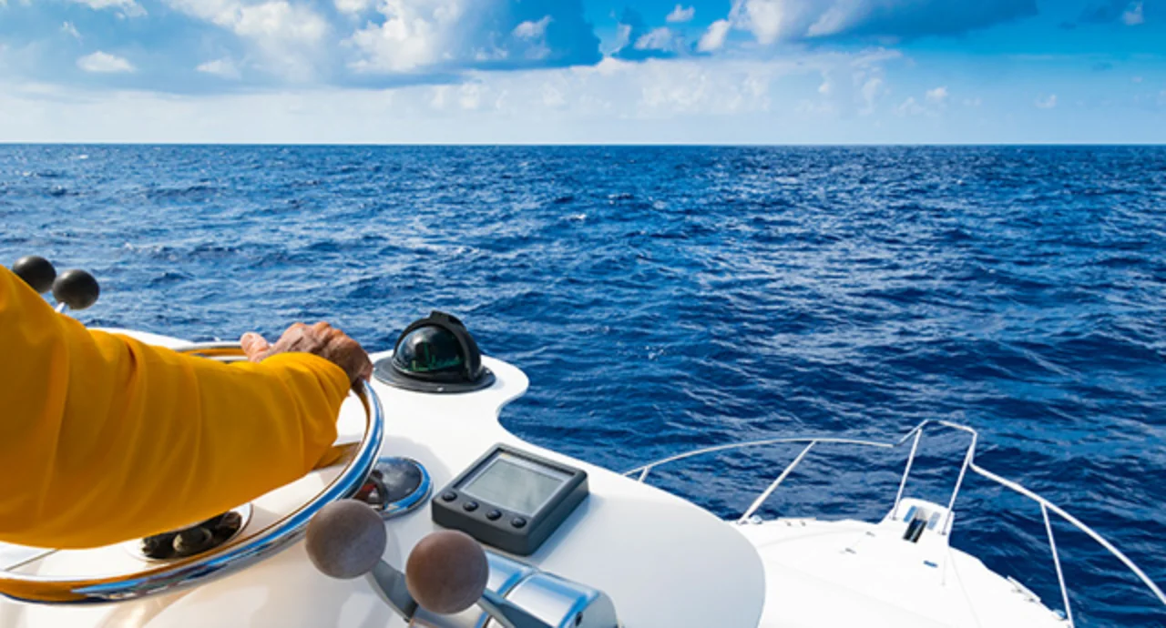 The hand of the captain at the wheel of a motorboat in the blue ocean