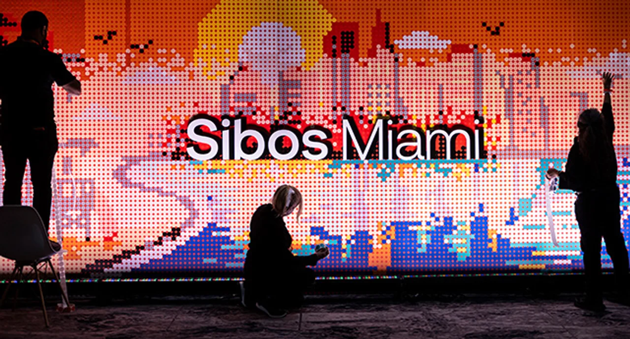 Attendees engage with an interactive digital art installation featuring a pixelated Miami skyline at the Sibos conference