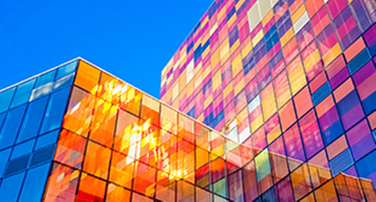 Two glass skyscrapers mirorring a myriad of colours