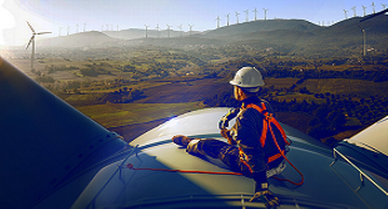 Windpower technician sitting atop a wind power generator