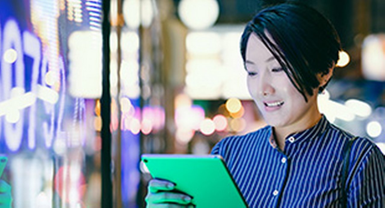 Businesswoman reading her tablet in front of a digital display in Hong Kong