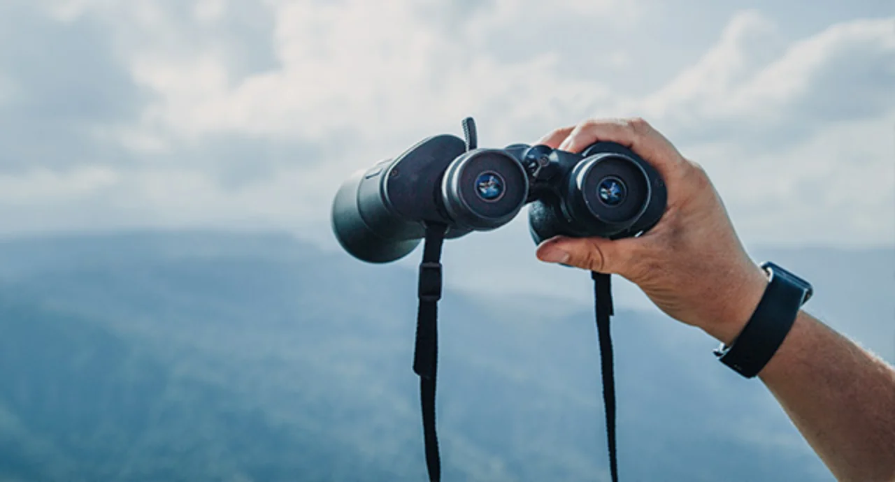 A man's hand holding binoculars