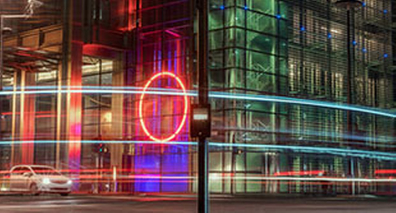 A car at a red light mirrored in a window at night