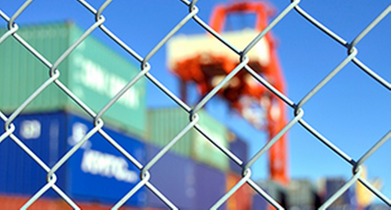 A wire mesh fence in front of a container yard