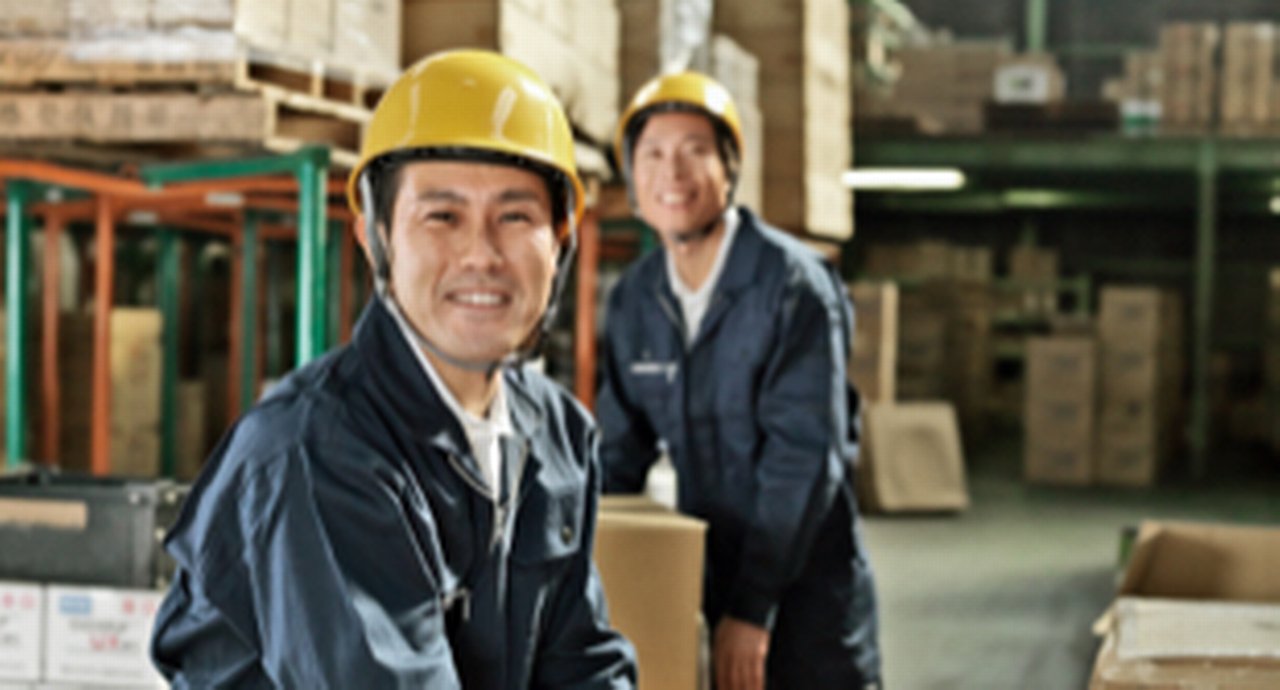 two smiling workers with safety helmets in a warehouse