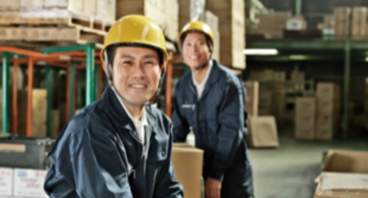 two smiling workers with safety helmets in a warehouse