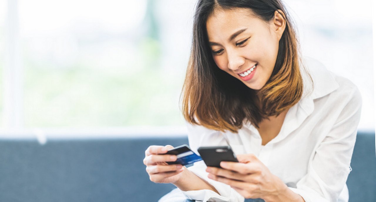 young asian woman using smartphone and credit card for online shopping