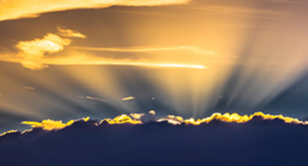 The sun shining behind dark clouds ready to break through