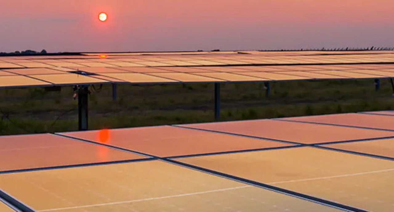 Solar panels at dusk with the sun in the background