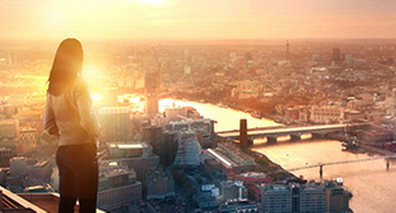Young woman looking over the city of London at sunset