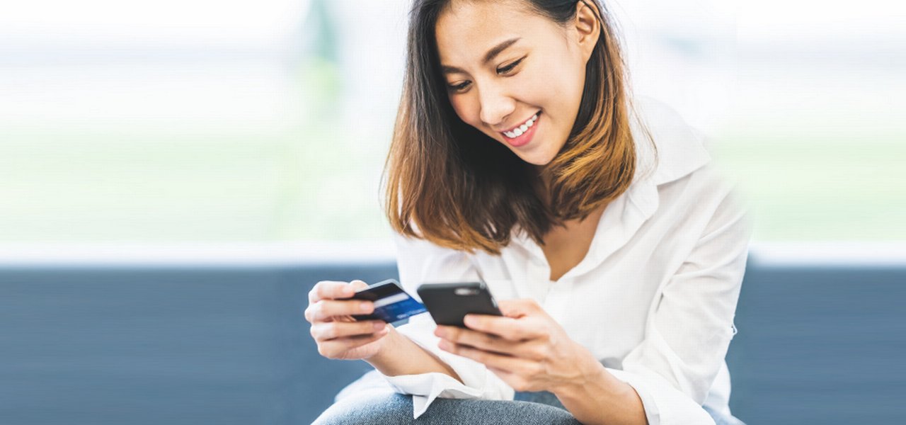 young asian woman using smartphone and credit card for online shopping