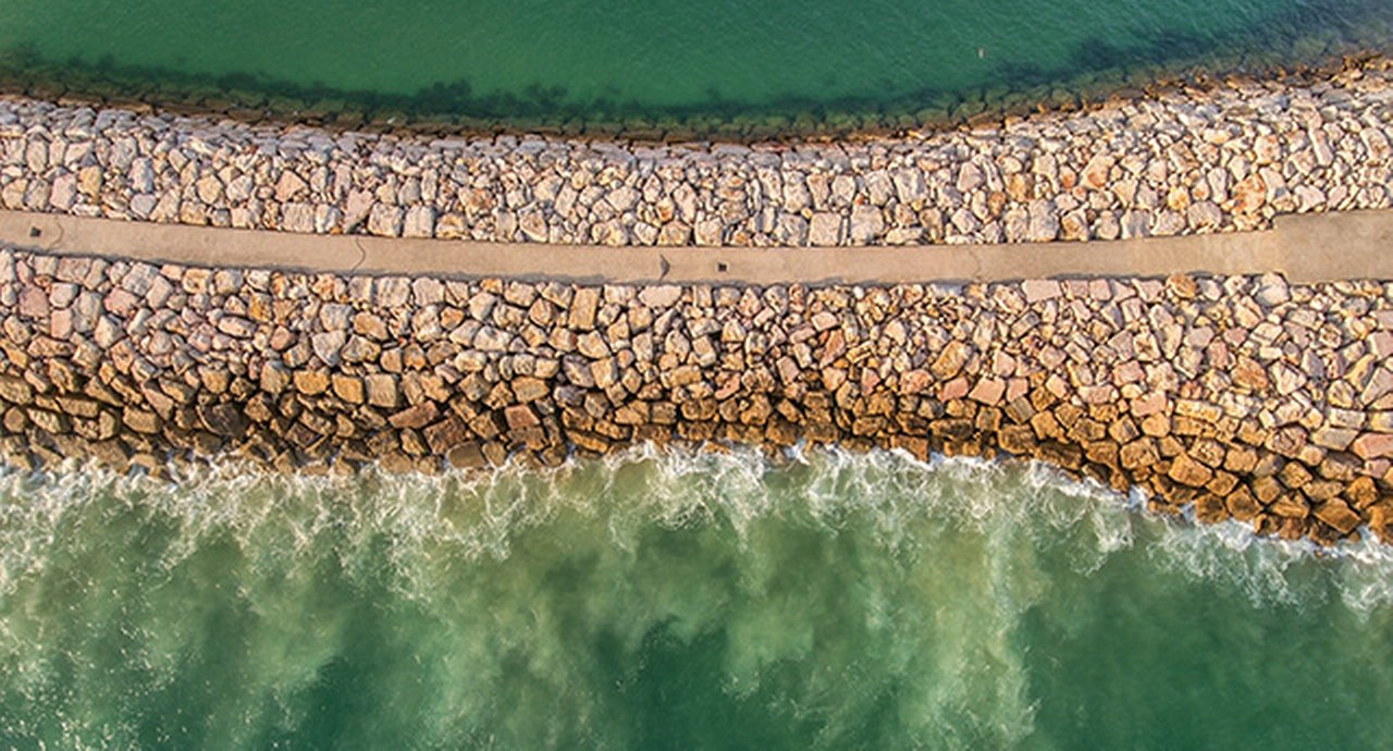 Aerial. Stone Industrial breakwater into the sea. Filmed from the sky. Portugal.
