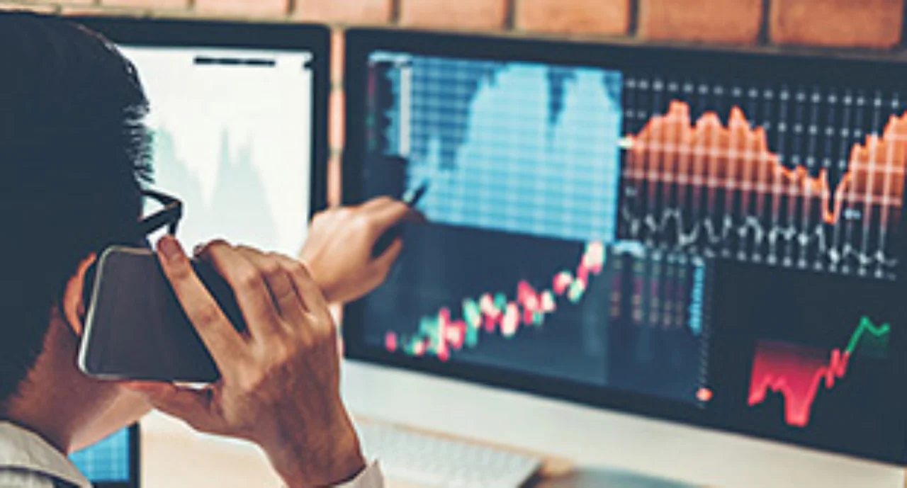 Person looking on charts displayed on his monitor whilst calling