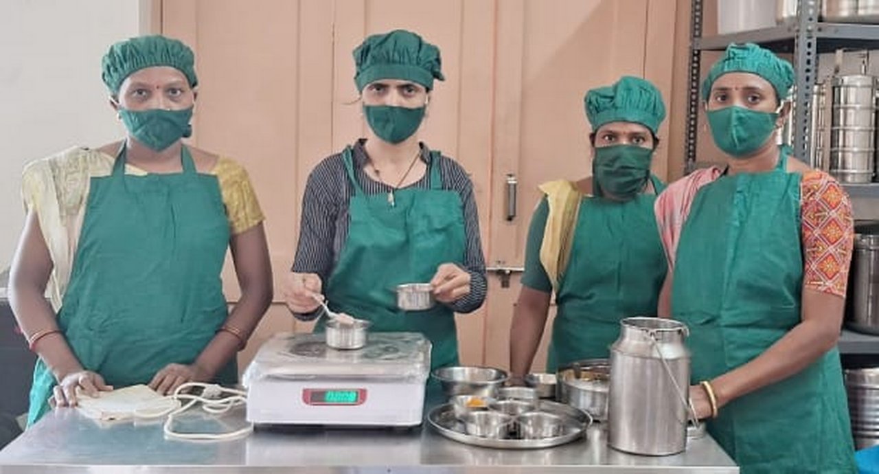 Four Kamla co-operative members wearing green protective clothing