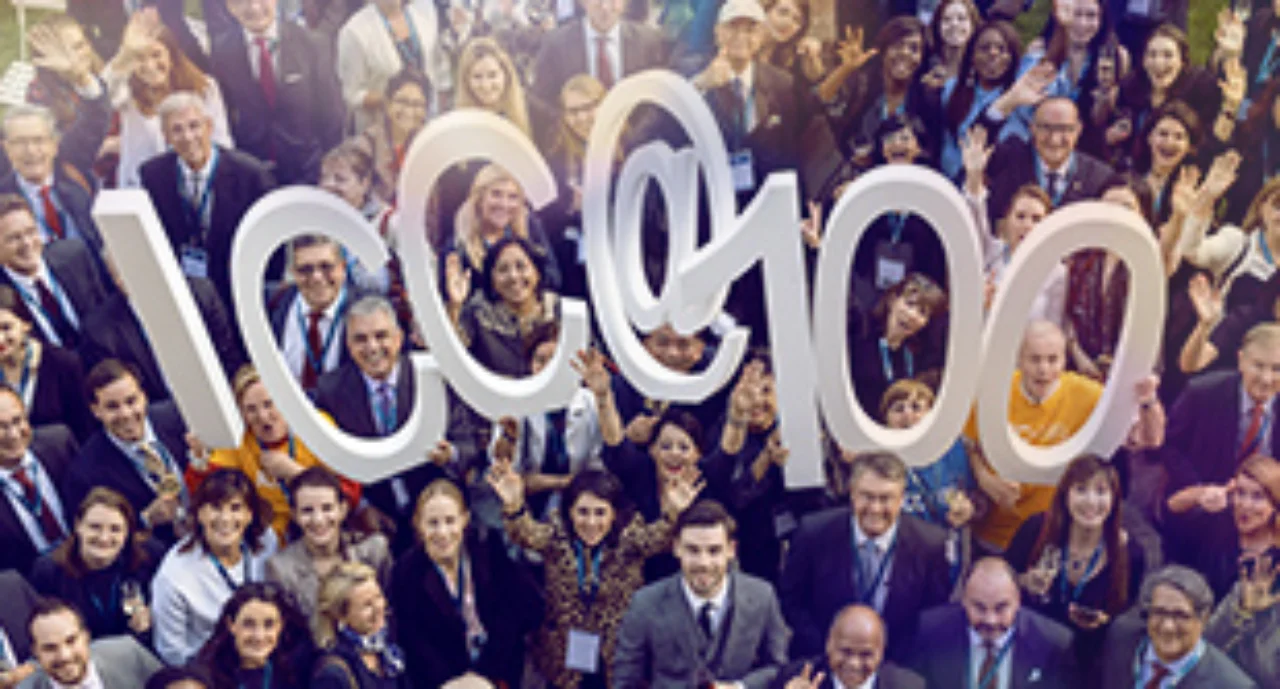 A crowd of cheering people holding ${esc.q}ICC @ 100${esc.q} in big singular letters
