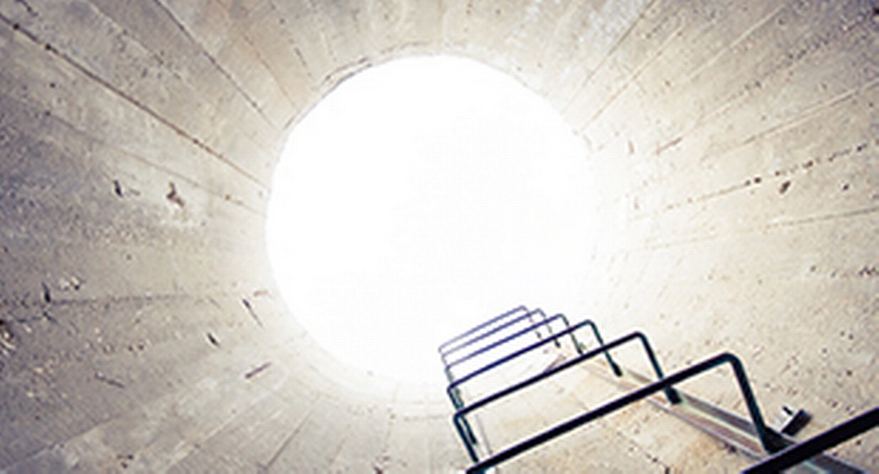 Image of a shaft with iron steps looking up into the light