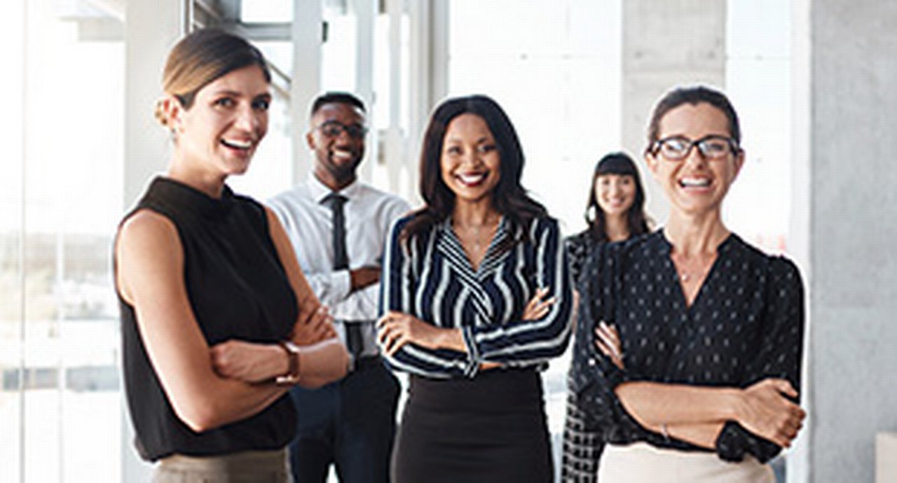 Shot of three businesswomen standing with colleagues in an office