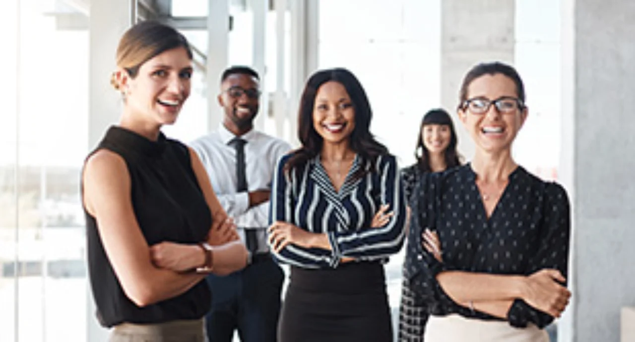 Shot of three businesswomen standing with colleagues in an office