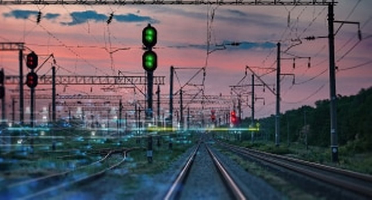 Train tracks, lights, and cables in the sunset