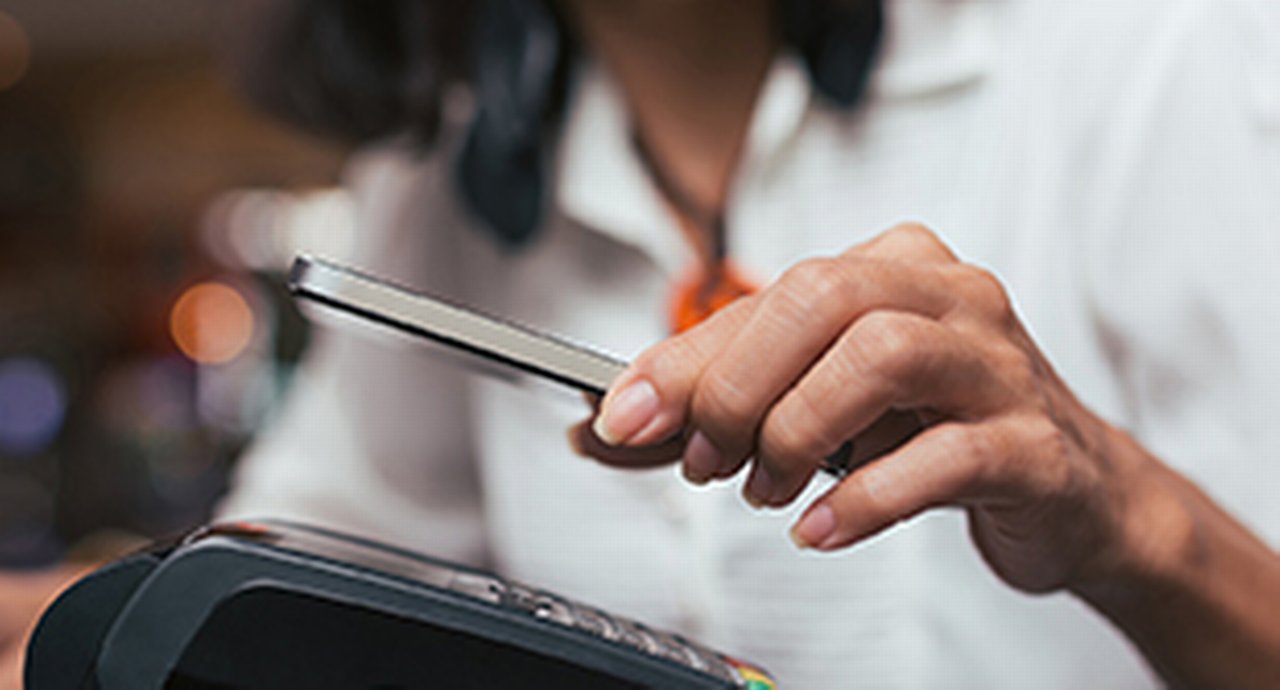 Close-up of a woman paying with her smartphone at a card machine