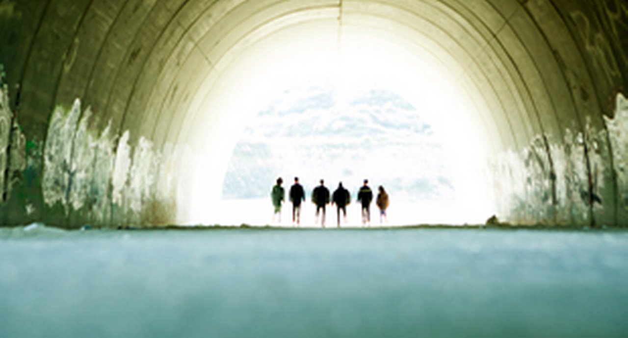 tunnel where 6 people are standing in the light at the end of the tunnel