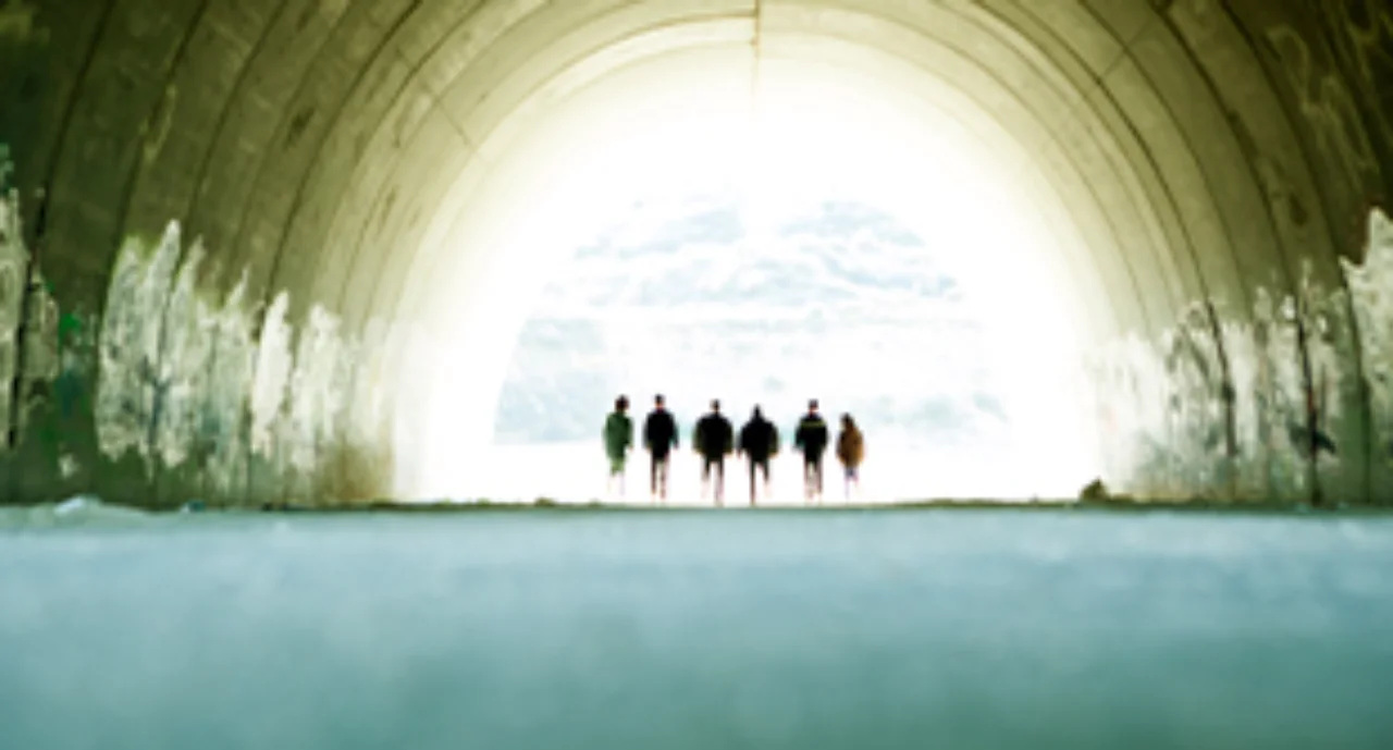 tunnel where 6 people are standing in the light at the end of the tunnel