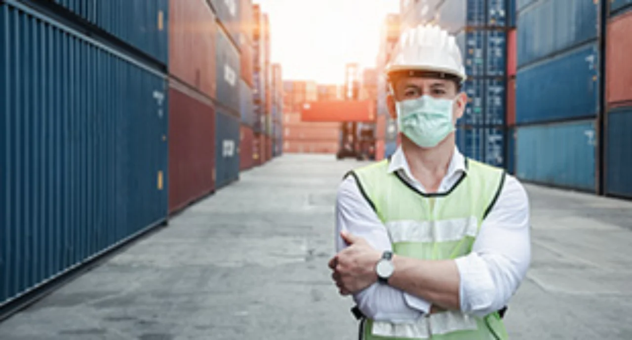 A masked worker in a container port