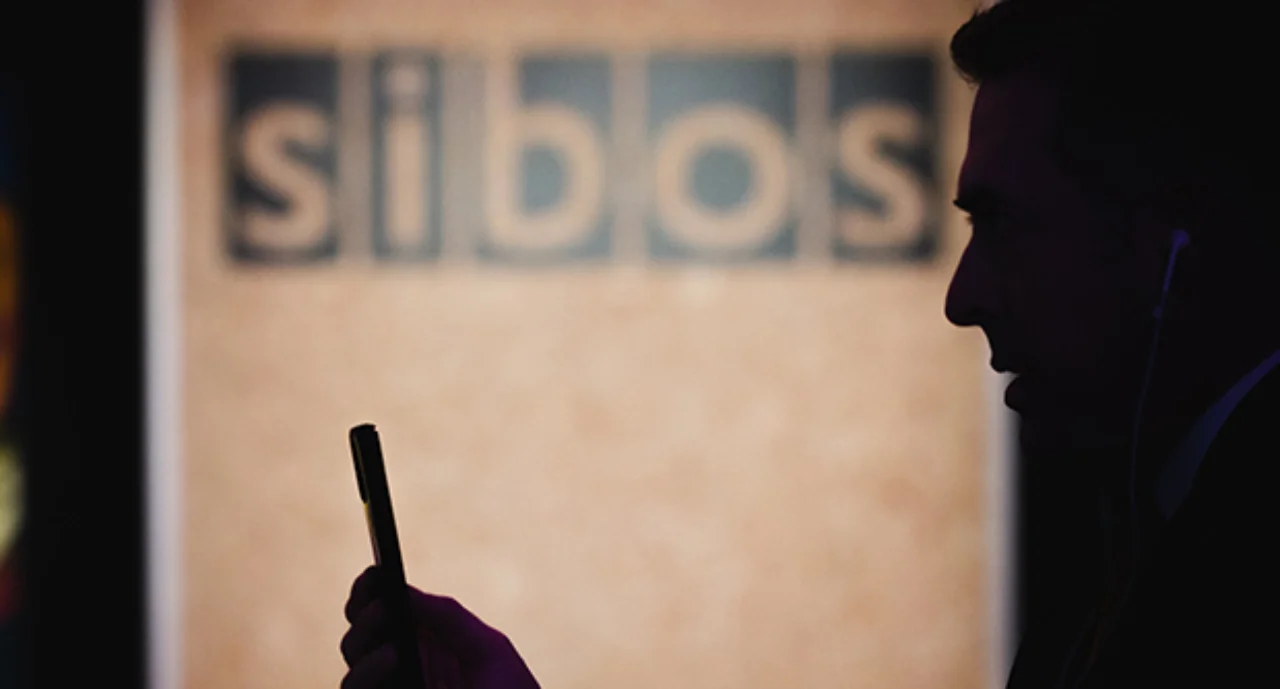 A person with a smartphone in front of a sibos image
