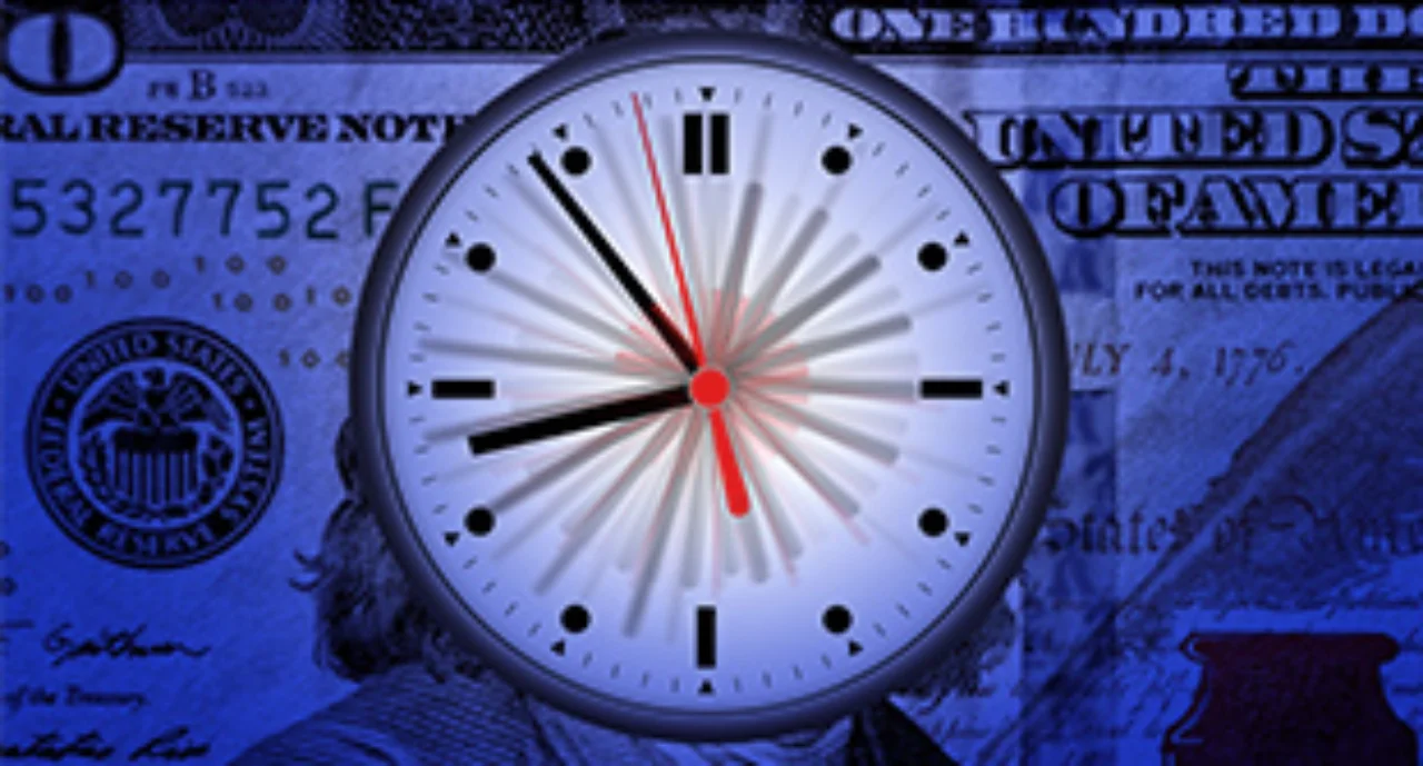 A clock in front of a hundred dollar bill