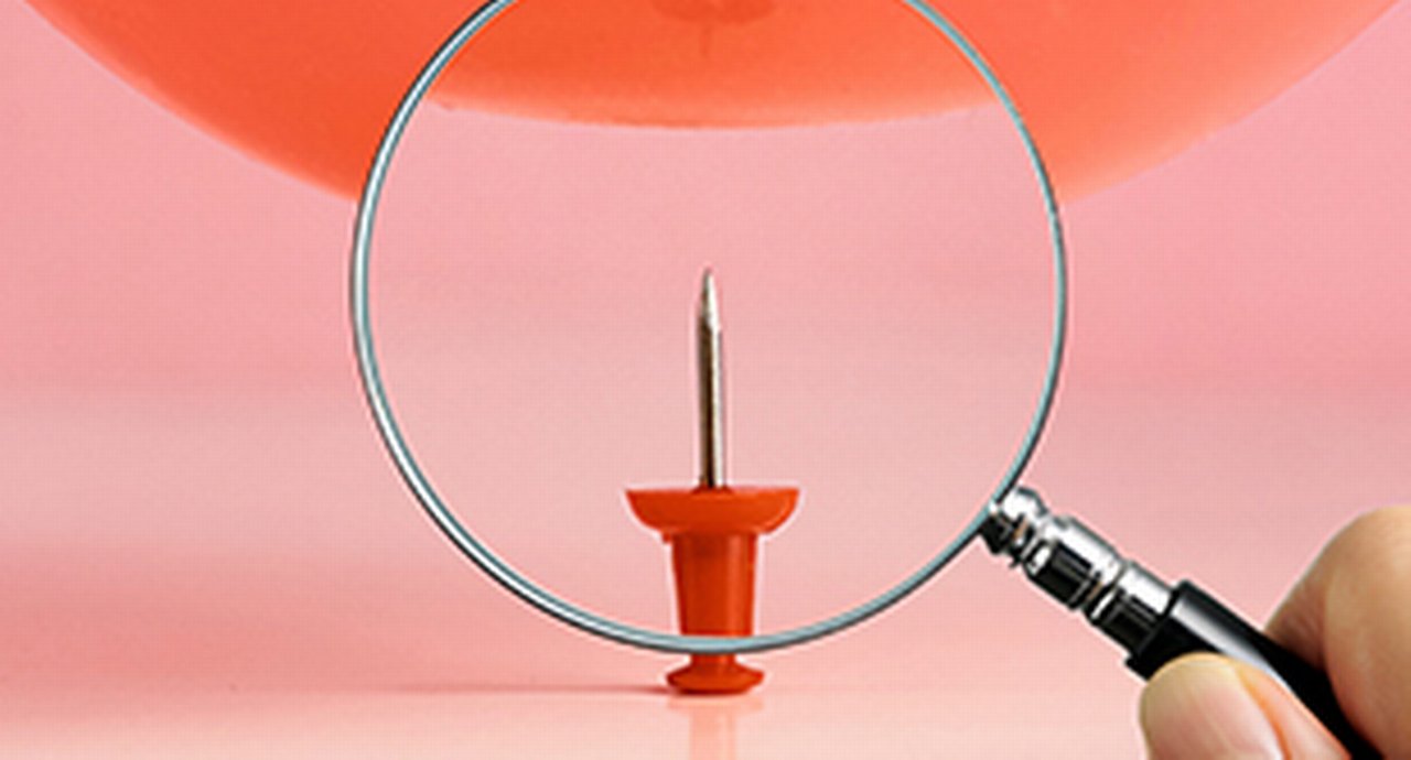 A red tack inspected with a magnifying glass
