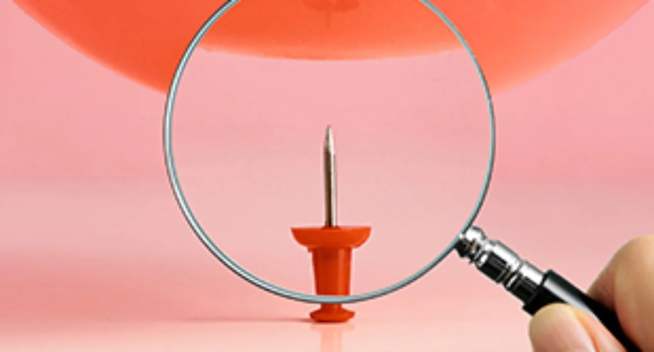 A red tack inspected with a magnifying glass
