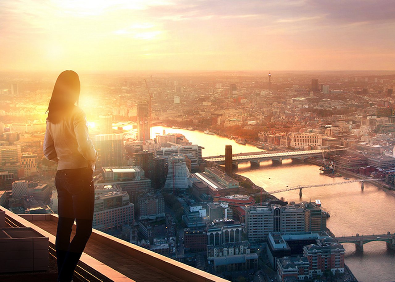Young woman looking over the city of London at sunset