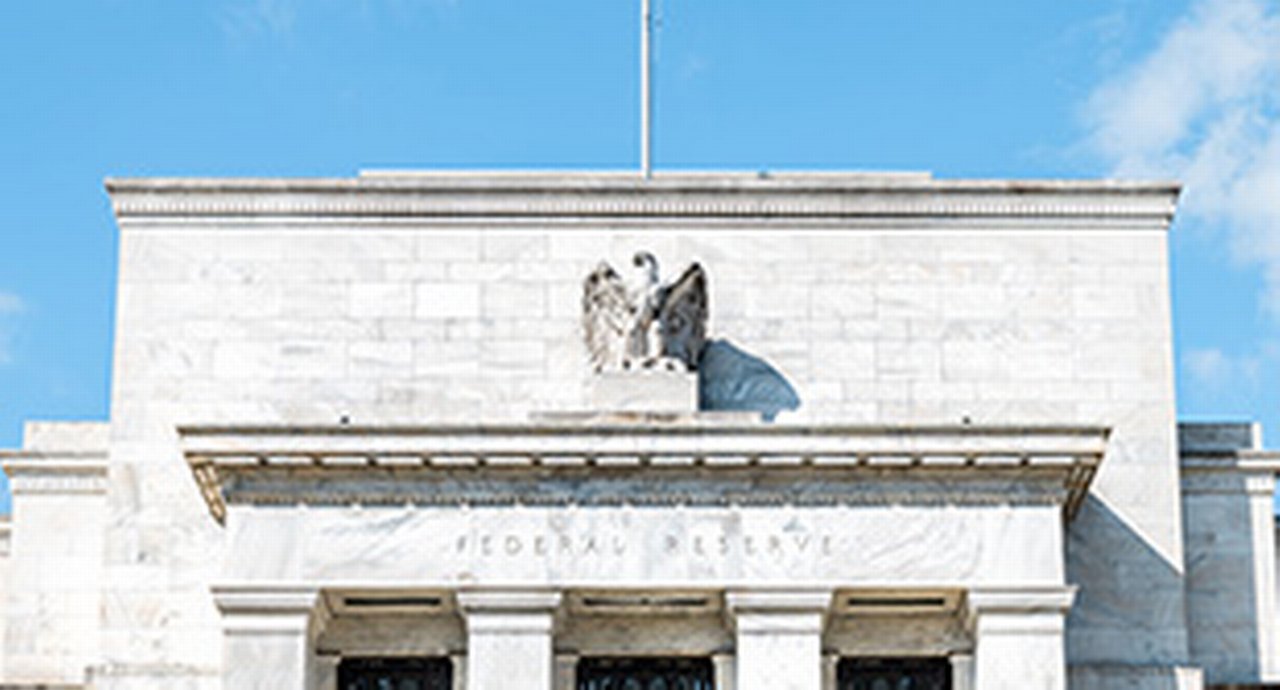 Closeup of Federal Reserve bank facade entrance, architecture building, eagle statue American flags, blue sky at sunny day