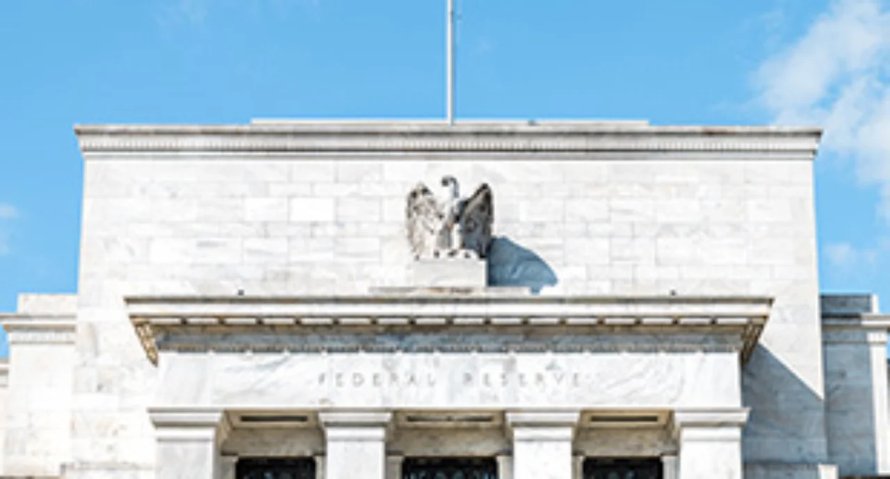 Closeup of Federal Reserve bank facade entrance, architecture building, eagle statue American flags, blue sky at sunny day