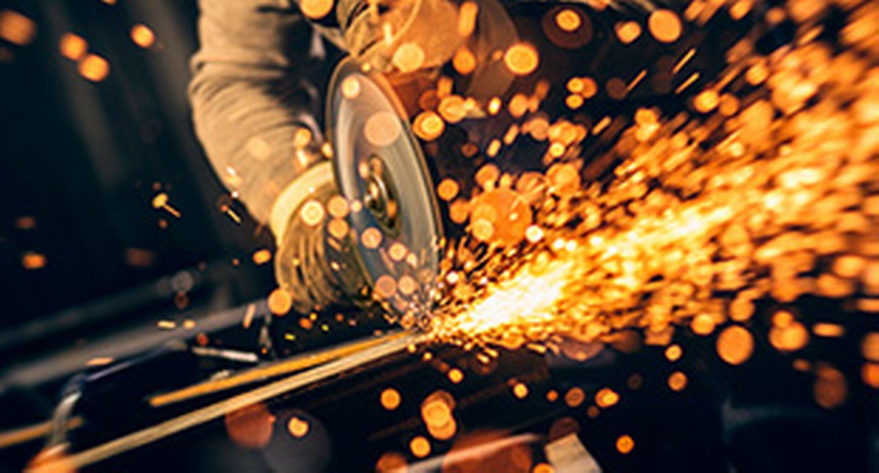 Metal worker cutting a metal objects with circular saw in small workshop