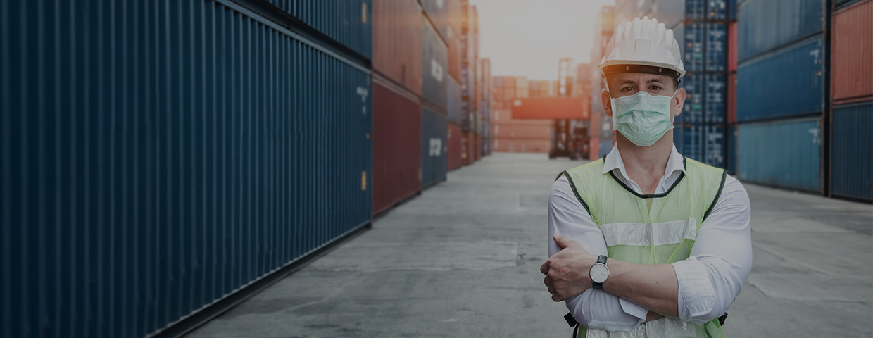 A masked worker in a container port