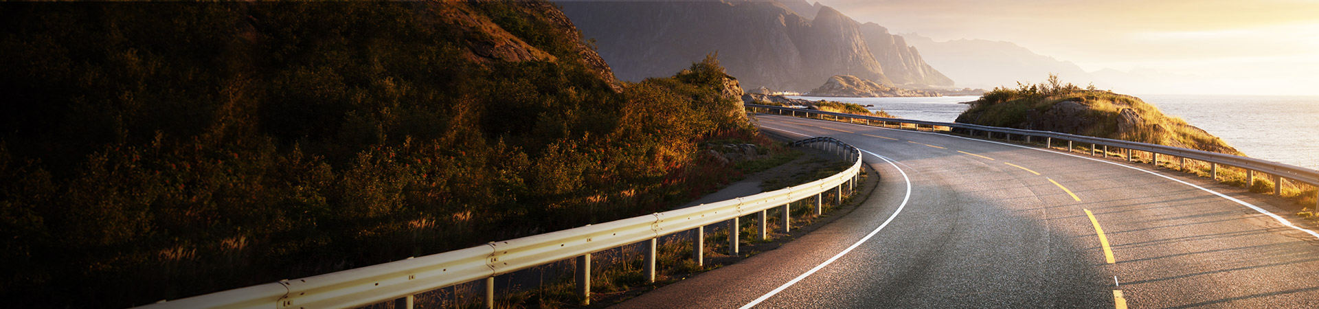 Scenic Coastal Highway with Serpentine Road and Ocean Views under Golden Hour Sunlight