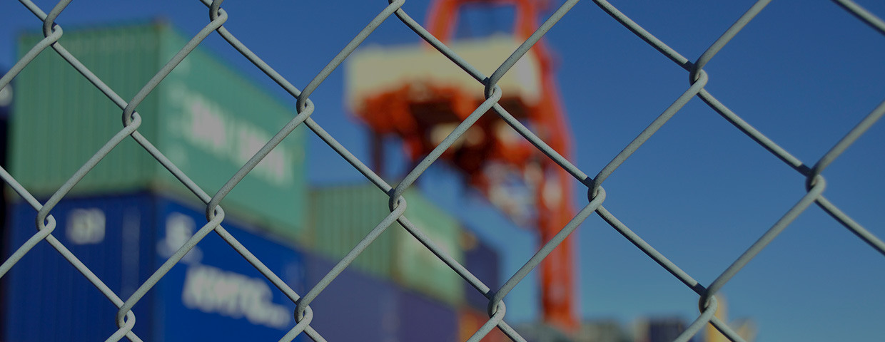 A wire mesh fence in front of a container yard