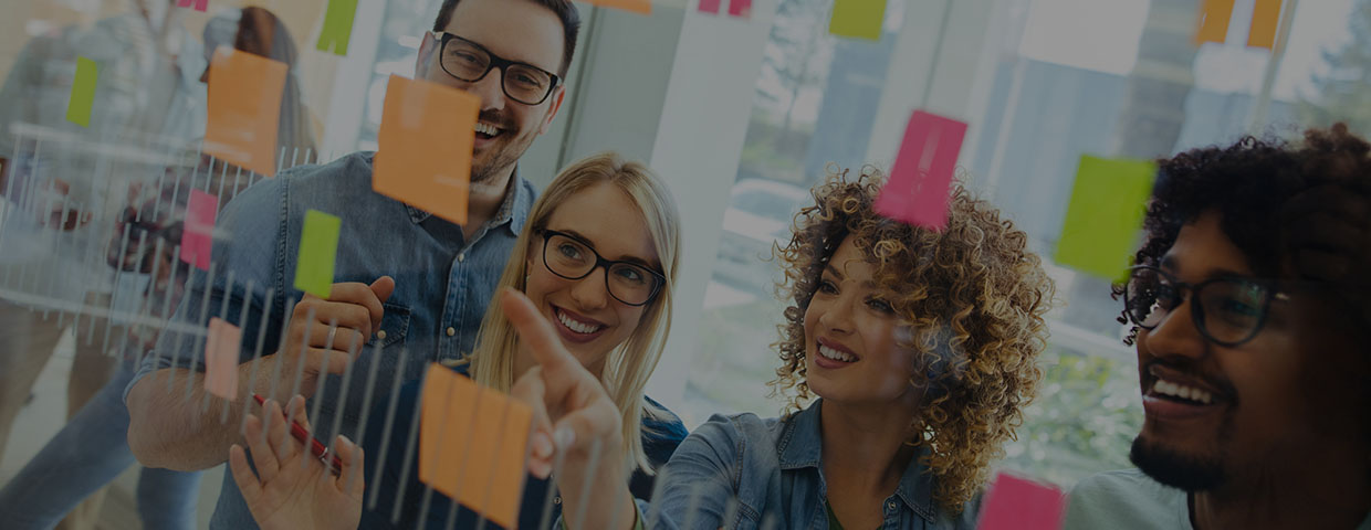 Business team brainstorming in front of glass wall with adhesive notes