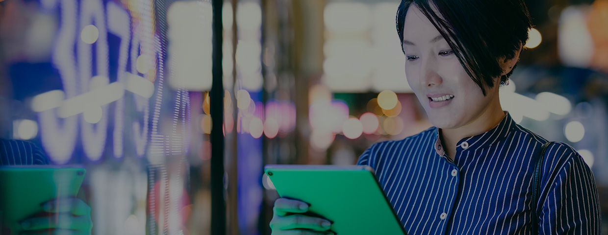 Businesswoman reading her tablet in front of a digital display in Hong Kong