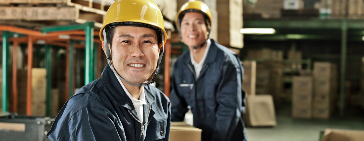 two smiling workers with safety helmets in a warehouse