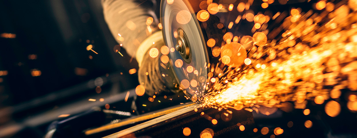 Metal worker cutting a metal objects with circular saw in small workshop