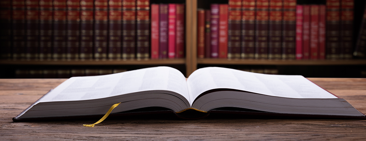 Close-up Of An Open Law Book On Wooden Desk In Courtroom