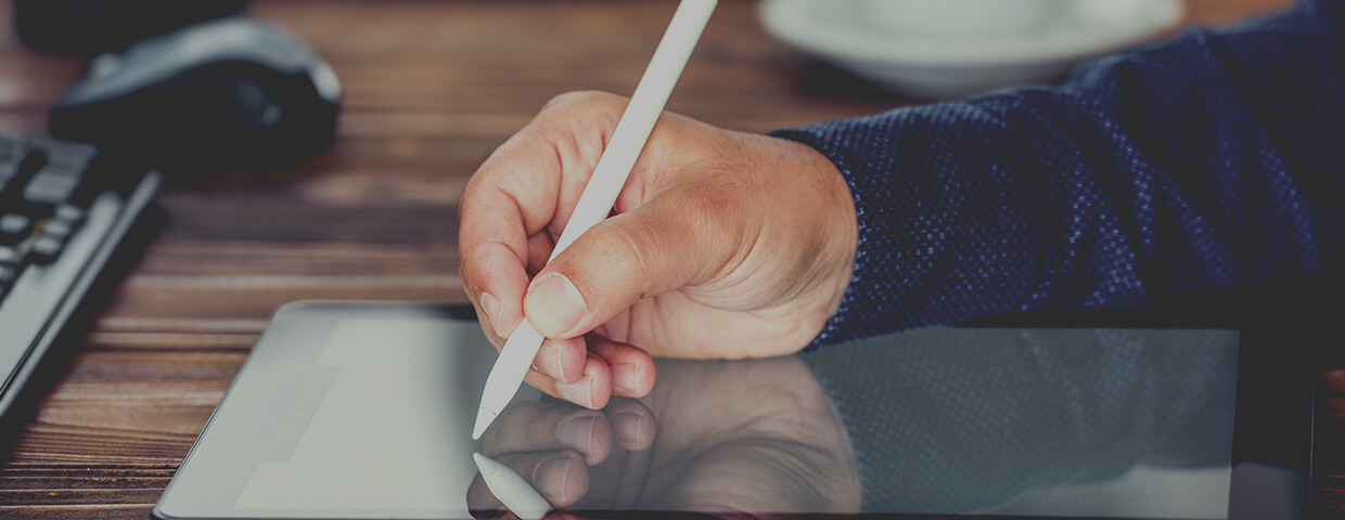 A hand in close-up signing digitally on a tablet